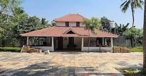 A two-story building with a tiled roof and a covered porch area.