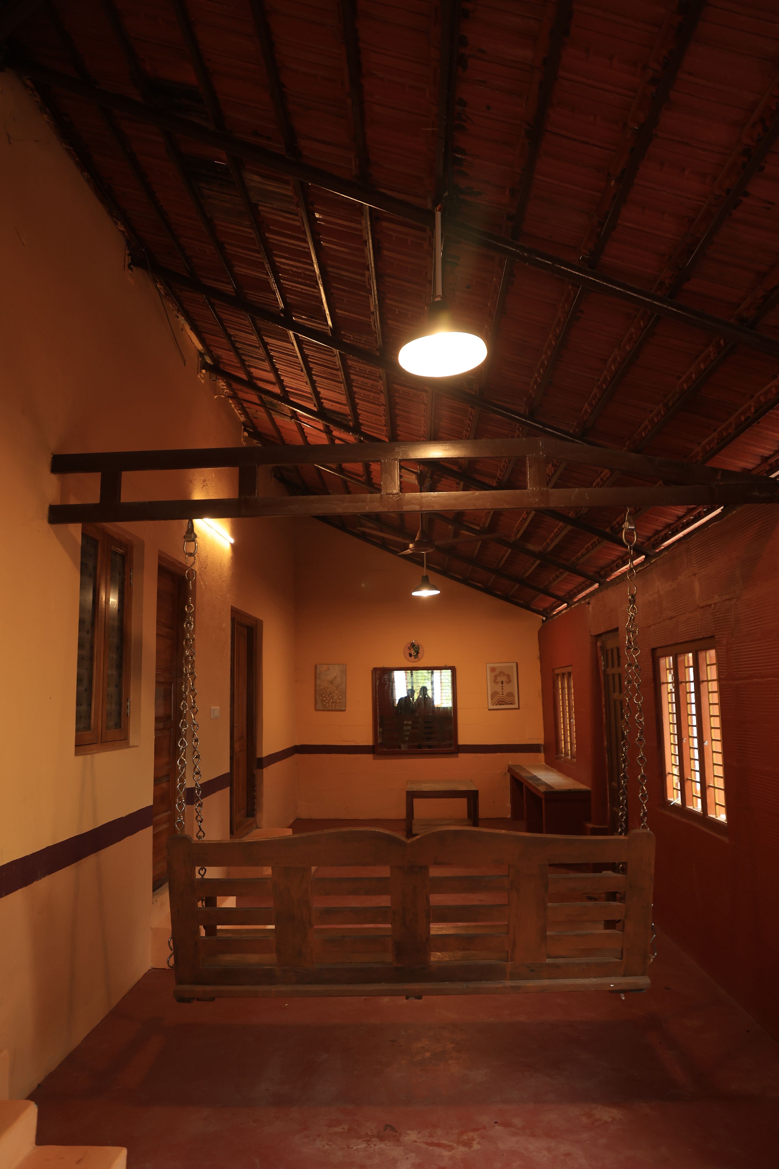 A room with a wooden bench, a ceiling fan, and a window with bars.
