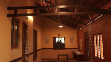 A room with a wooden bench, a ceiling fan, and a window with bars.