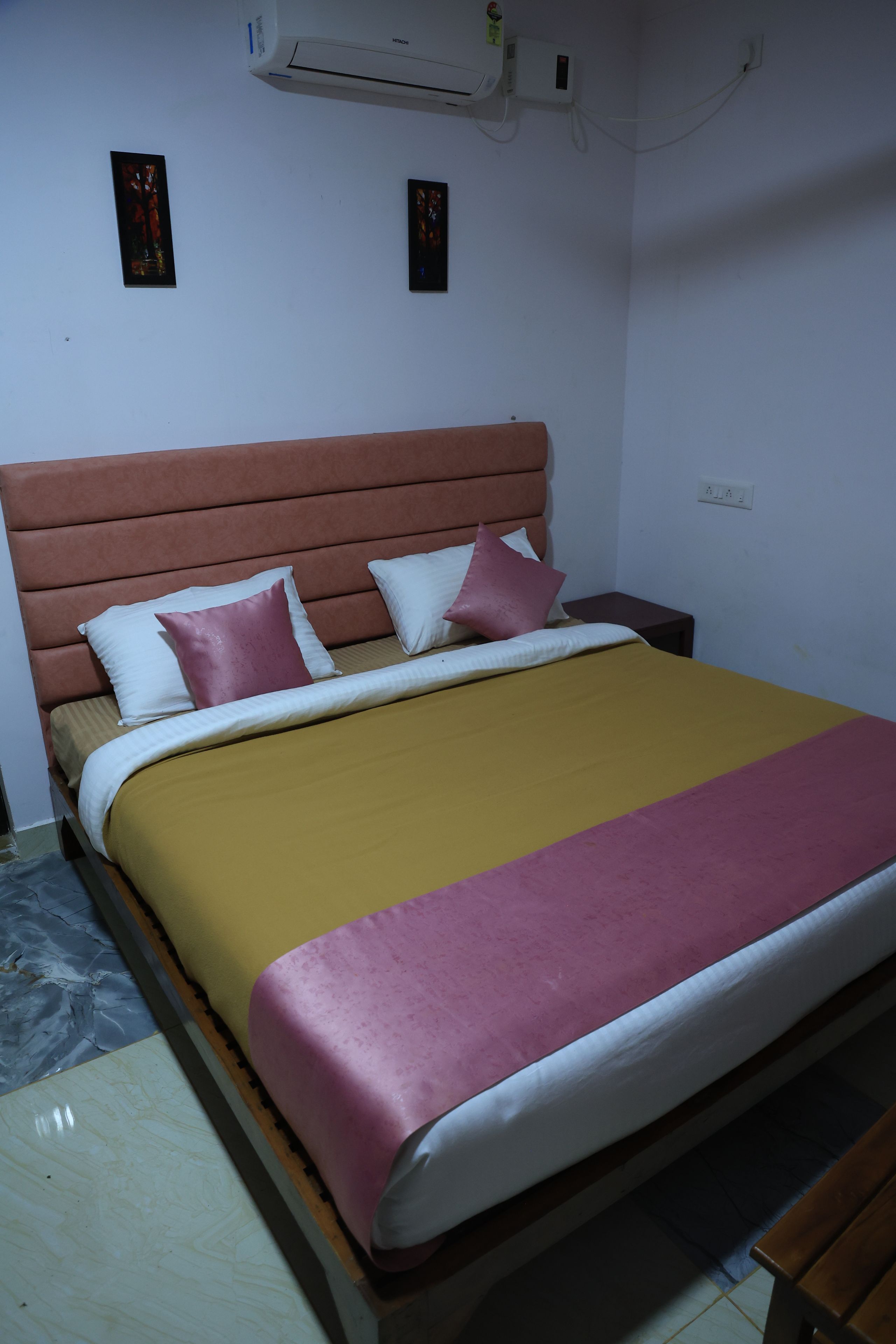 A bed with a headboard, two bedside tables, and a wall-mounted air conditioner.