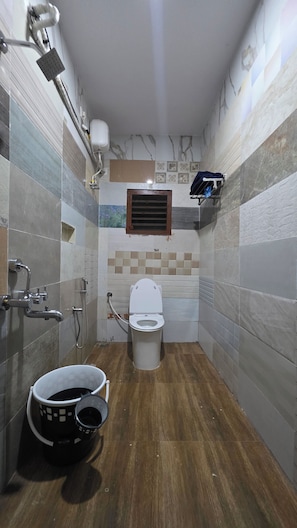 A bathroom with a toilet, shower, and sink.