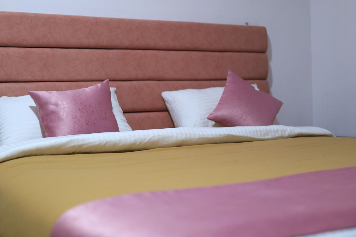 A bed with a headboard, pillows, and a blanket.