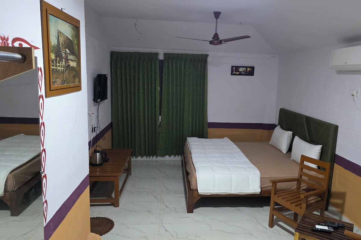 A hotel room with two beds, a ceiling fan, an air conditioning unit, a television, and a small table with a kettle.