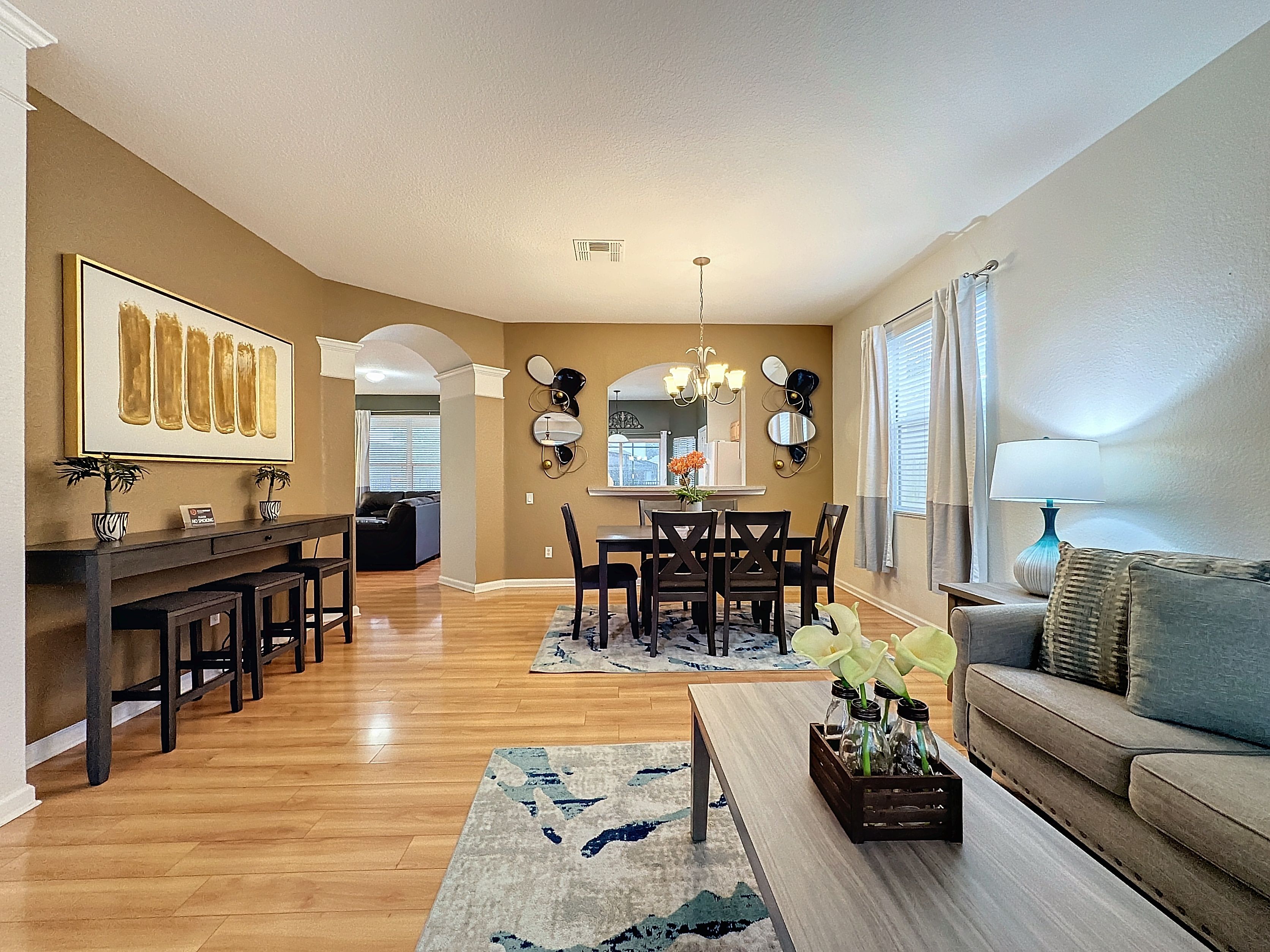 A spacious living room with a dining area, hardwood floors, and a large window providing natural light.