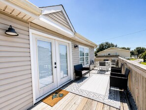 A residential property with a covered patio, a door with a glass panel, and a small outdoor seating area. - 3 BR, Walk to the Beach Townhouse in Surfside Beach! Sandy Sea (Surfside Beach)