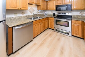 A kitchen with wooden cabinets, a stainless steel dishwasher, a microwave, and an oven. - 2BR Oceanfront Condo with Elevator and Shared Pool! South Shores II 203 (Surfside Beach)