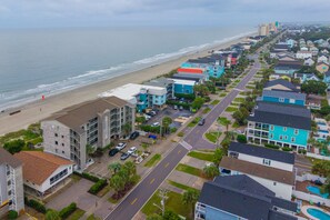 Zona residencial costeira com propriedades à beira-mar, uma estrada principal e uma praia.