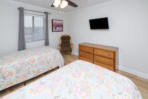 A bedroom with two single beds, a wooden dresser, a chair, a television, and a window with blinds. - 2BR Oceanfront Condo with Elevator and Shared Pool! Surfwatch II 302 (Surfside Beach)