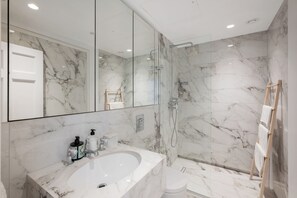 A modern bathroom with a marble sink, a glass shower enclosure, and a wooden towel rack. - Spacious 1-Bed in the Heart of Marylebone, London (London)