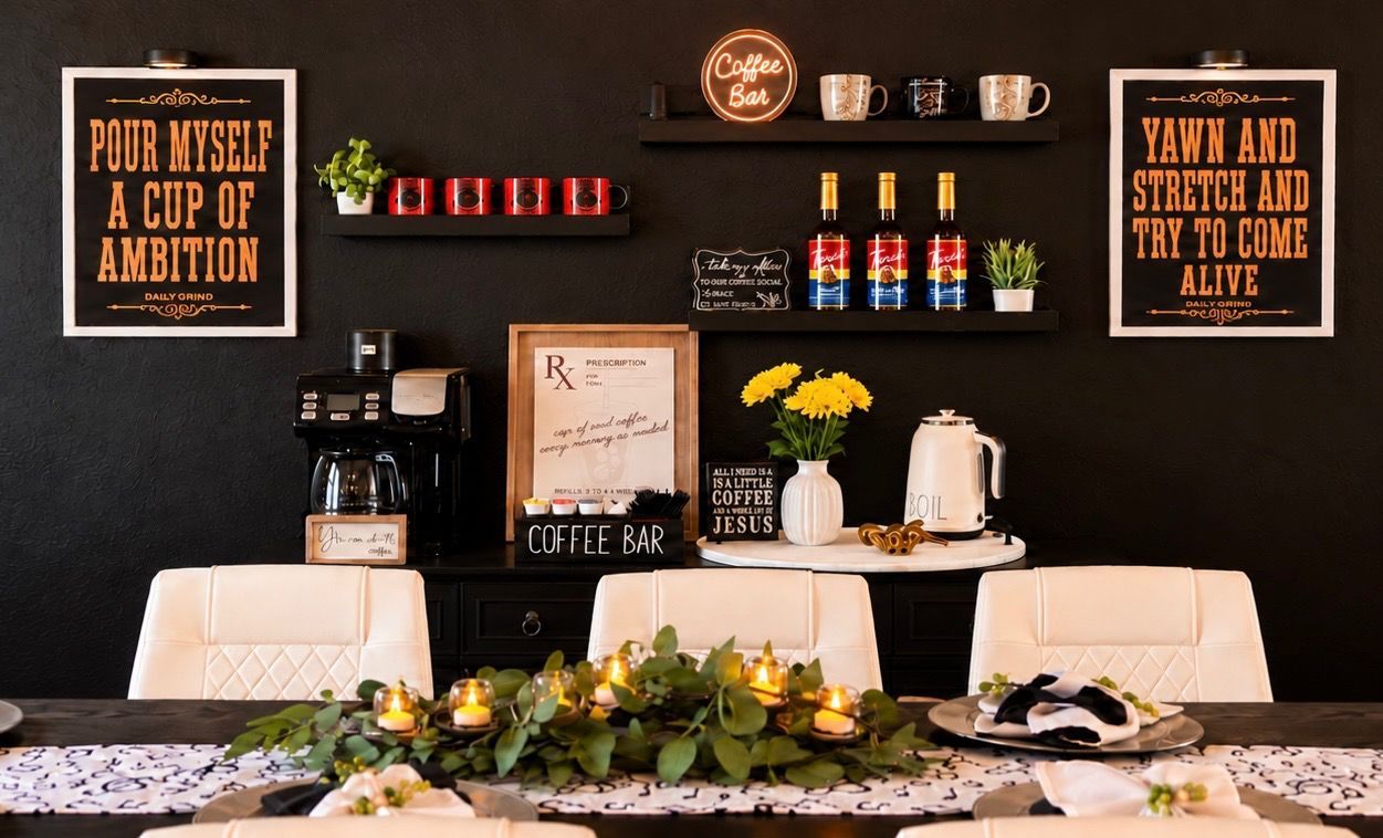 Un coin café aménagé avec une machine à café, des tasses et un panneau indiquant « Bar à café ». On y trouve également des citations inspirantes encadrées et une petite plante en pot accrochée au mur.