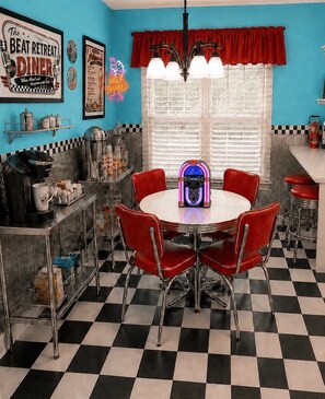 Ein Diner im Stil der 1950er Jahre mit Schachbrettboden, roten Stühlen, einem Neonlicht und einer alten Jukebox.
