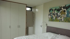 Een slaapkamer met een bed, een kledingkast, een schilderij en een raam.