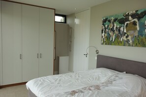 Ein Schlafzimmer mit Bett, Kleiderschrank, einem Gemälde und einem Fenster.