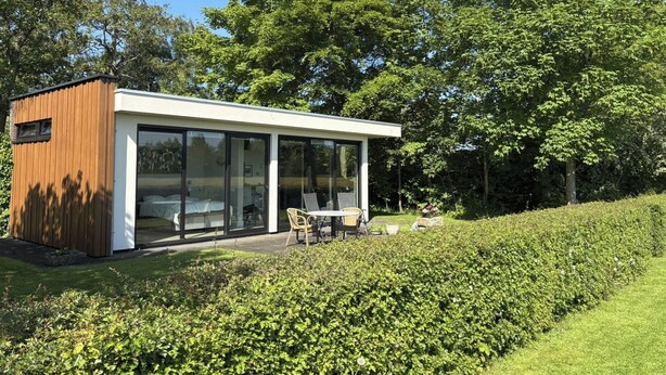 Een modern, gelijkvloers huis met een glazen gevel, een houten buitenkant en een tuin.
