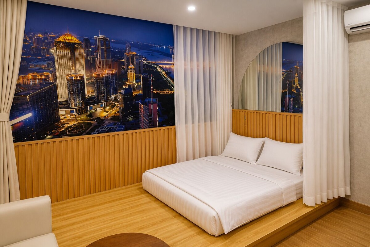 Ein Hotelzimmer mit einem Bett, Holzvertäfelung, Blick auf die Stadt und einem großen Fenster mit Vorhängen.