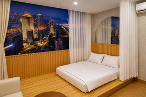 Ein Hotelzimmer mit einem Bett, Holzvertäfelung, Blick auf die Stadt und einem großen Fenster mit Vorhängen.
