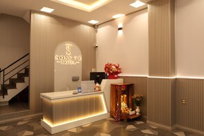 Ein Hotelrezeptionstresen mit modernem Design, eine Treppe links und eine an der Wand befestigte Überwachungskamera.