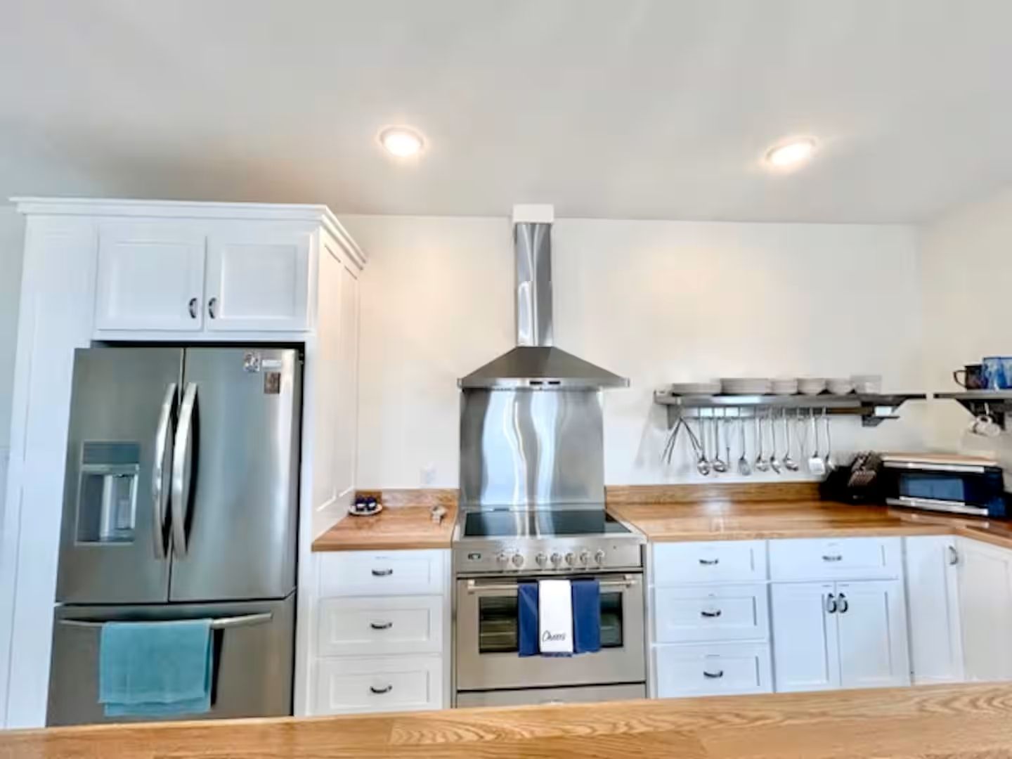 A kitchen with white cabinets, a stainless steel refrigerator, a gas stove, and a microwave.