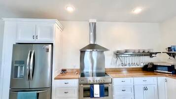 A kitchen with white cabinets, a stainless steel refrigerator, a gas stove, and a microwave.