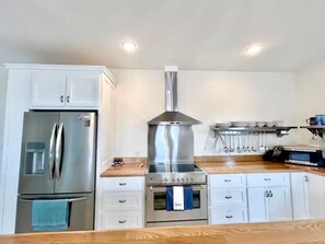 A kitchen with white cabinets, a stainless steel refrigerator, a gas stove, and a microwave.