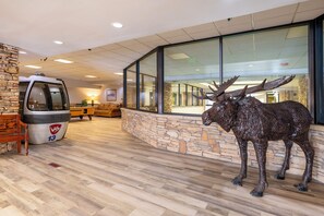 A lobby with a stone wall, a wooden bench, a luggage cart, and a moose statue. - Silverado II Unit 631 Exquisite 4 bedroom penthouse, private deck, clubhouse (Winter Park)