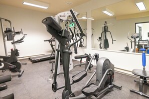 Une salle de sport équipée de divers appareils d’exercice, notamment des tapis de course et des appareils de musculation, et dotée d’un grand miroir mural.