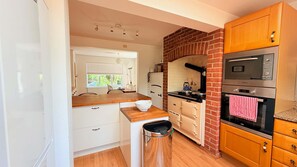 A compact kitchen with a brick wall, white cabinetry, a wooden countertop, and a stainless steel oven. - Dutch Cottage Spacious 2-bed w Large Garden (Halstead)