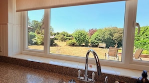 A kitchen with a large window, granite countertop, and a stainless steel faucet. - Dutch Cottage Spacious 2-bed w Large Garden (Halstead)