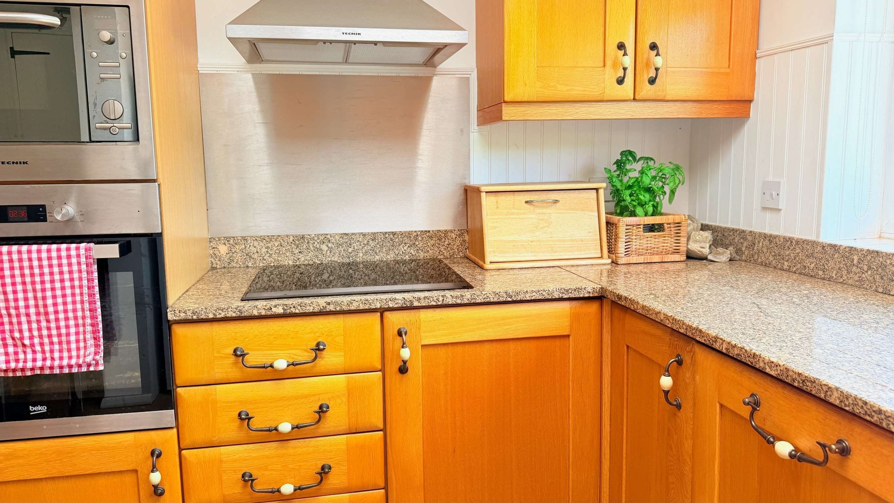 A kitchen with wooden cabinets, a built-in oven, a microwave, and a granite countertop.
