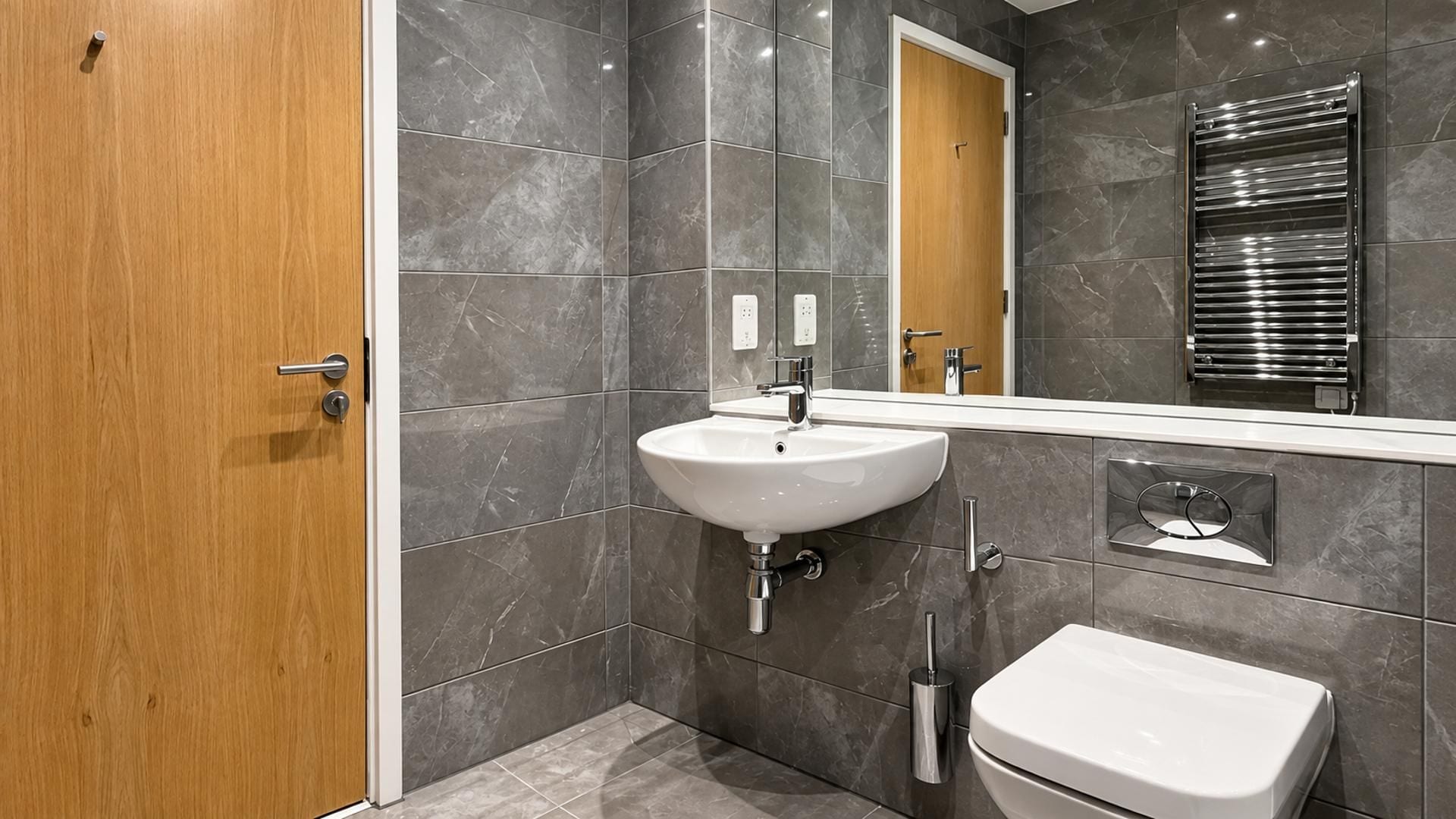 Ein modernes Badezimmer mit Holztür, Waschbecken in Weiß, Spiegel und Handtuchhalter.