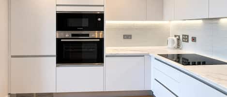 A modern kitchen with white cabinetry, a Bosch oven, a built-in stovetop, and a tiled backsplash.