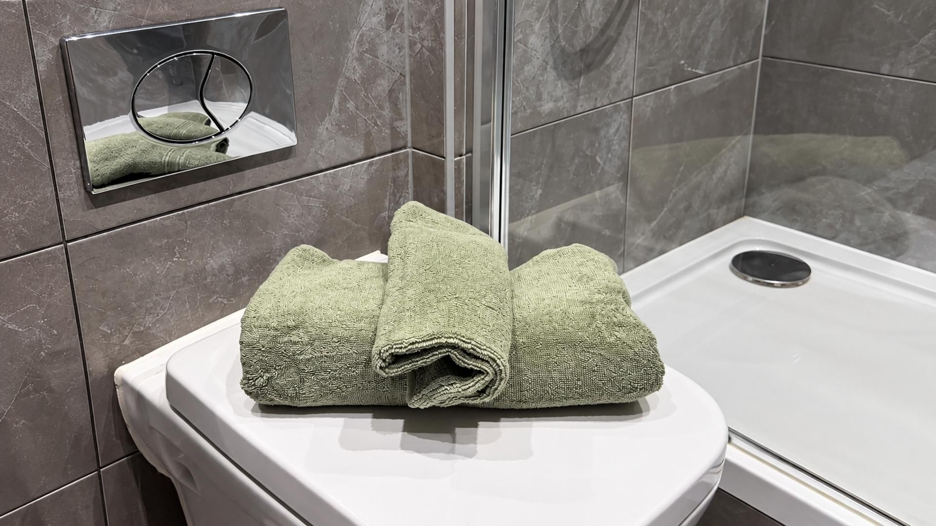 A bathroom with a white toilet, a towel on the seat, and a mirror with a towel inside.