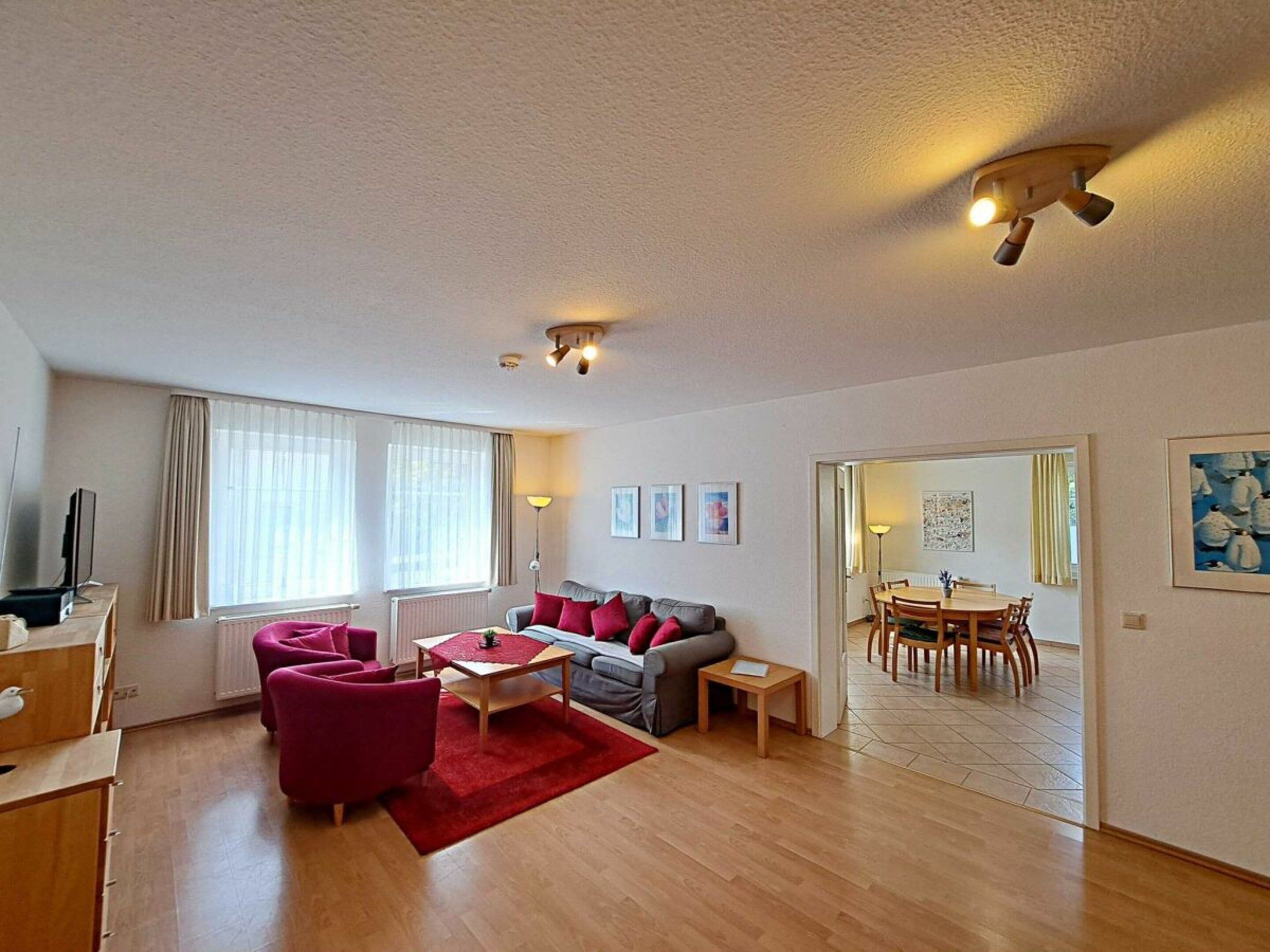 Een moderne woonkamer met een bank, fauteuils, een salontafel en een eethoek met een tafel en stoelen.