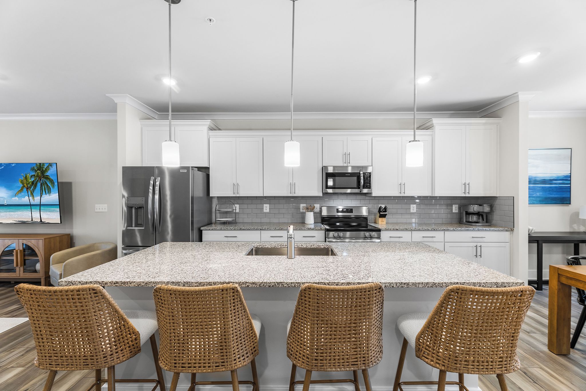 A modern kitchen with a central island, stainless steel appliances, and a dining area with wicker chairs.