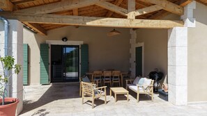 Eine Außenpatio mit Holzmöbeln, einem Grill und einem Blumentopf.