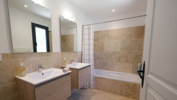A modern bathroom with two sinks, a bathtub, and a shower.
