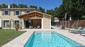 A residential property with a swimming pool, outdoor seating, and a fenced garden.