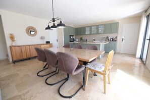 A modern kitchen with a central island, a dining area with a wooden table and four chairs, and a light fixture above the table.