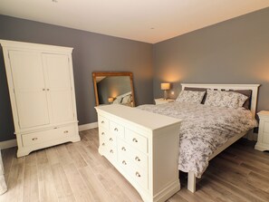 Ein Schlafzimmer mit Bett, Kommode, Kleiderschrank und Spiegel.