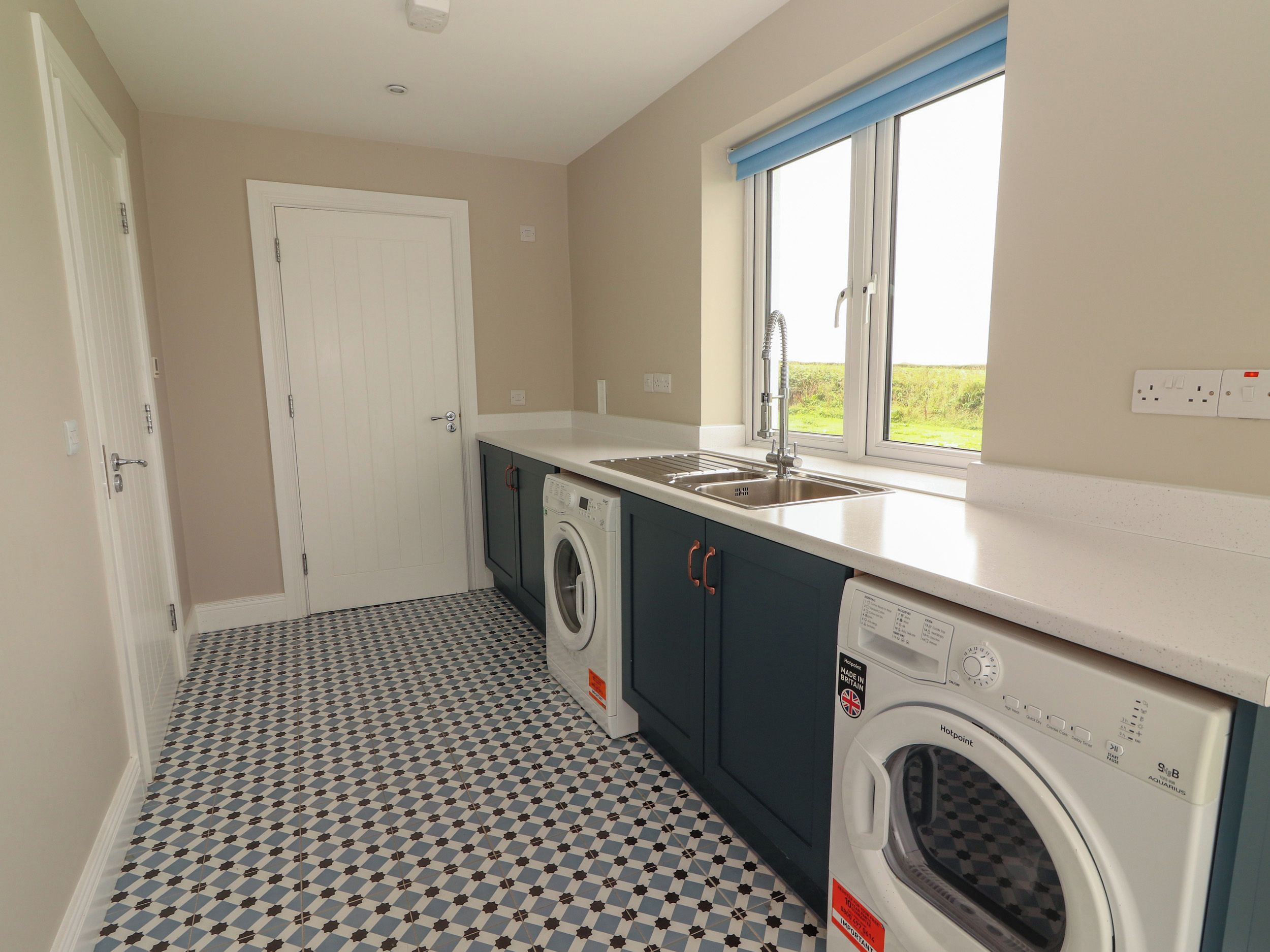A compact kitchen with a washing machine, a sink, and a window with a view.