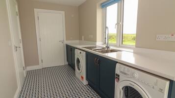 A compact kitchen with a washing machine, a sink, and a window with a view.