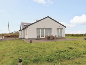 A single-story house with a patio, a dining table, and chairs.