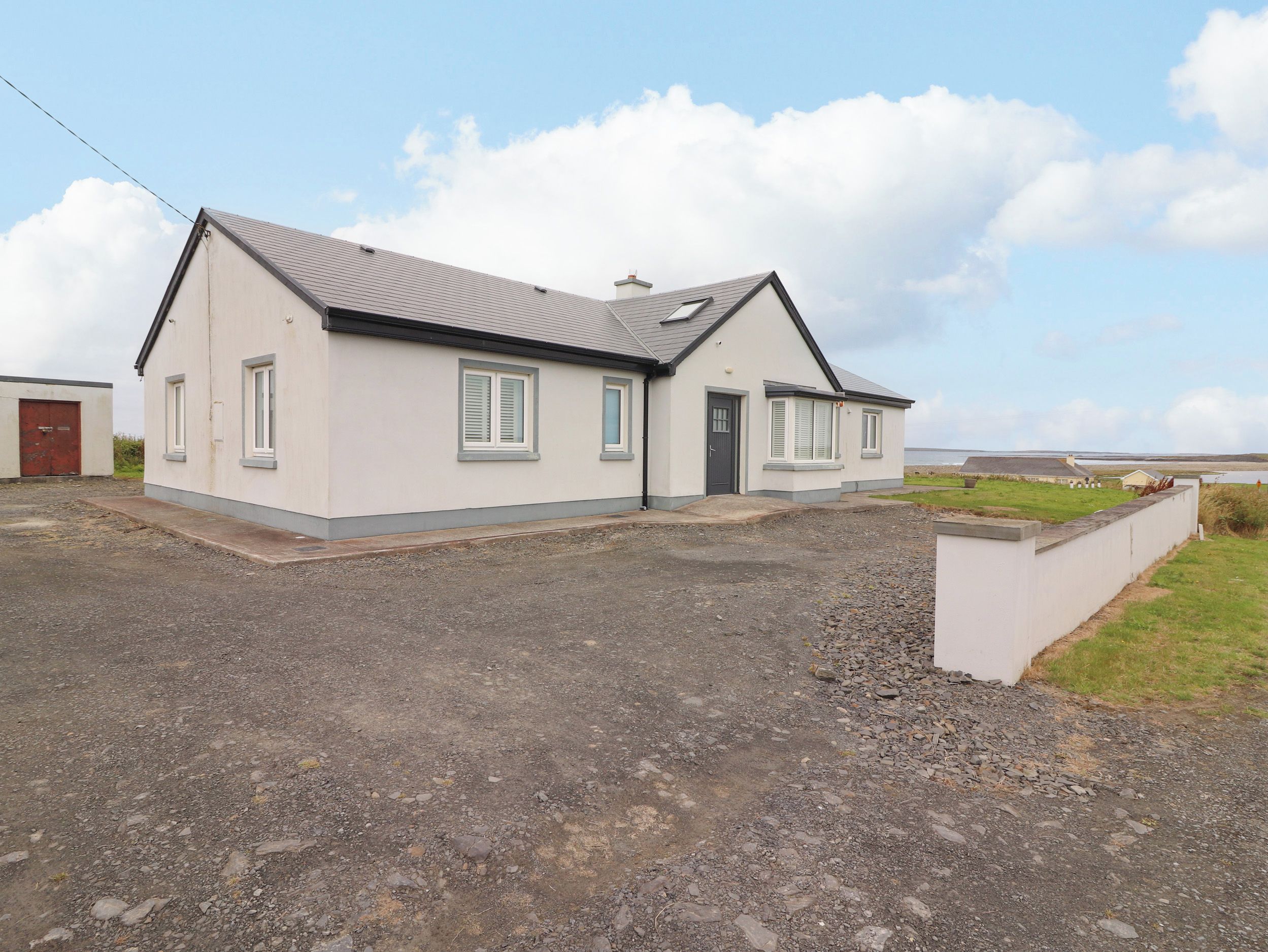 A single-story house with a gravel driveway and a grassy area in front.