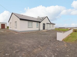 A single-story house with a gravel driveway and a grassy area in front.