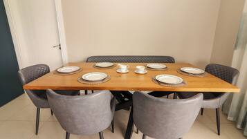 A dining table with six chairs, plates, and a pitcher.