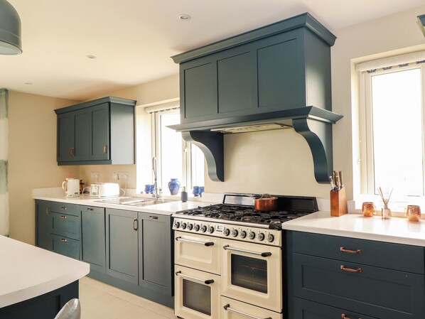 A kitchen with dark blue cabinets, a white countertop, a stove, and a sink. - CEOL NA MARA, family friendly, with a garden in Doonbeg, County Clare (Doonbeg)