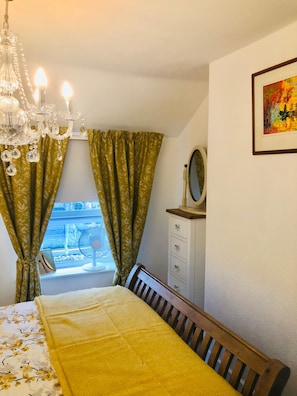 A bedroom with a bed, a dresser, a mirror, a chandelier, and curtains. - Tranquil Dolgellau Cottage Retreat (Dolgellau)