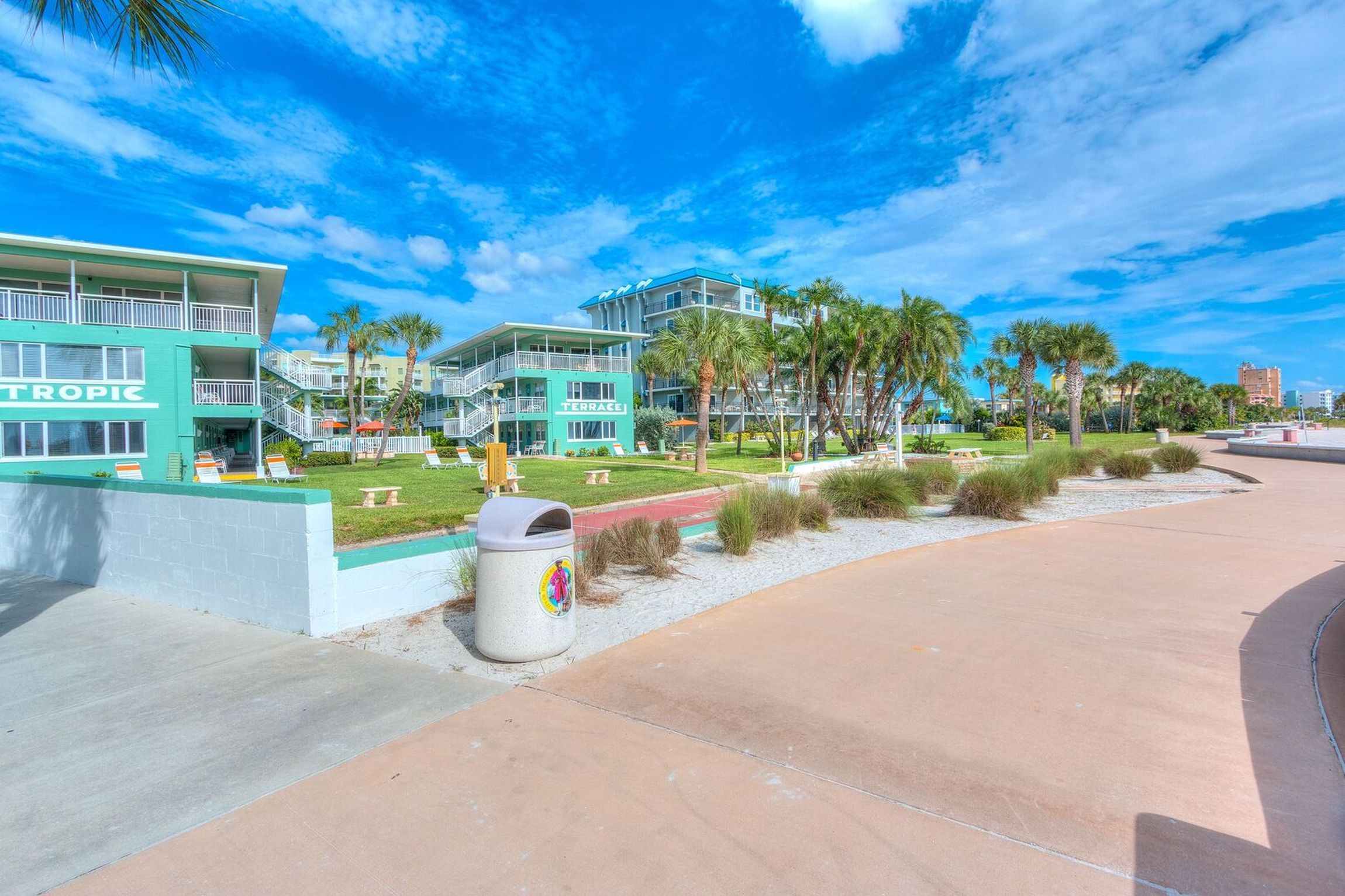 Ein Hotel mit Poolbereich, Palmen und blauem Himmel.