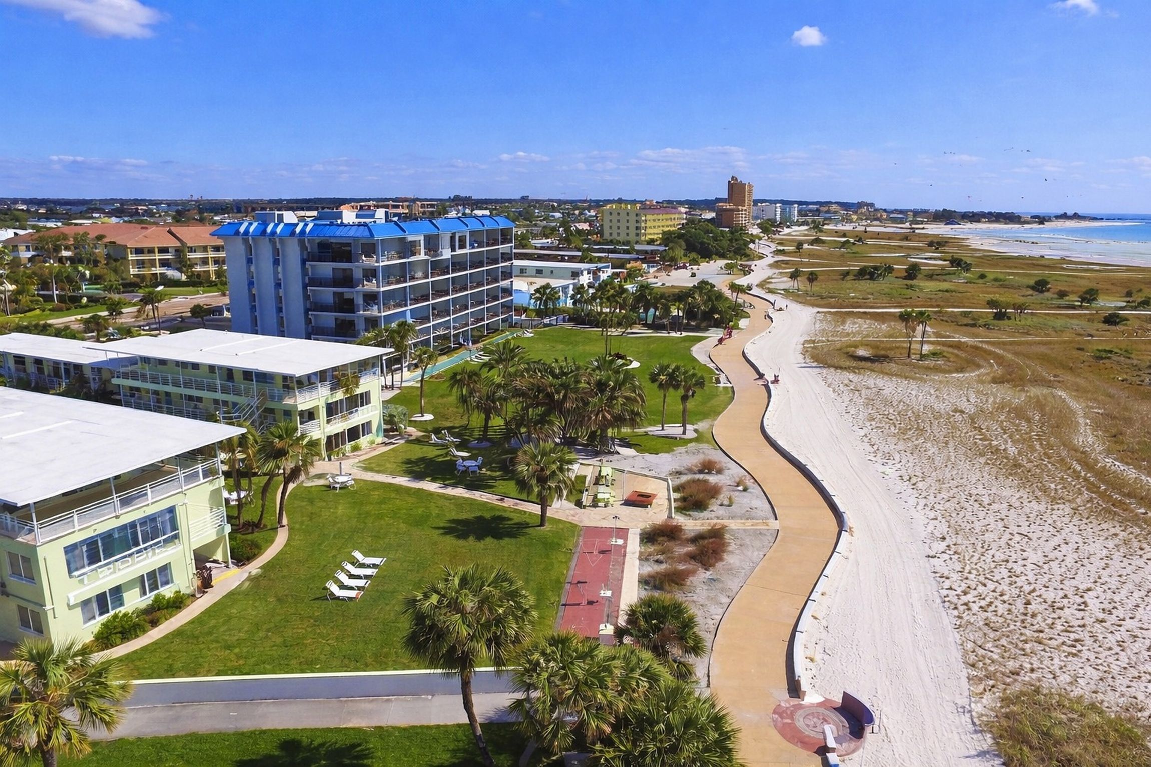 Ein Küstenhotel mit Blick auf den Strand, mehrstöckigen Gebäuden und einem gepflegten Rasen.
