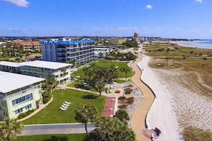 Ein Küstenhotel mit Blick auf den Strand, mehrstöckigen Gebäuden und einem gepflegten Rasen.